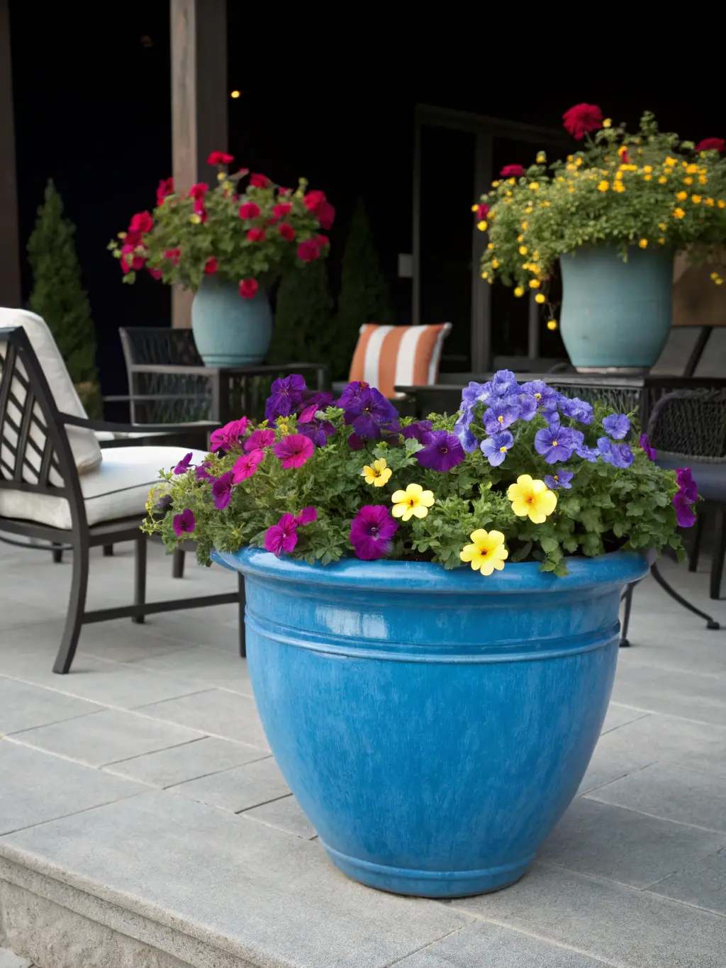 A close-up shot of a vibrant, red rotomolded pot filled with colorful seasonal flowers, placed on a patio with festive decorations in the background, showcasing its durability and aesthetic appeal for the festive season.