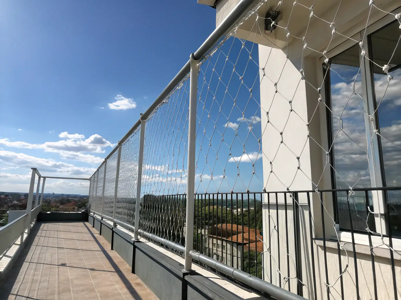 A high-resolution image showing bird netting and invisible grills installed on a residential balcony, with a clear view of the cityscape in Gandhinagar, highlighting safety and unobtrusive design.